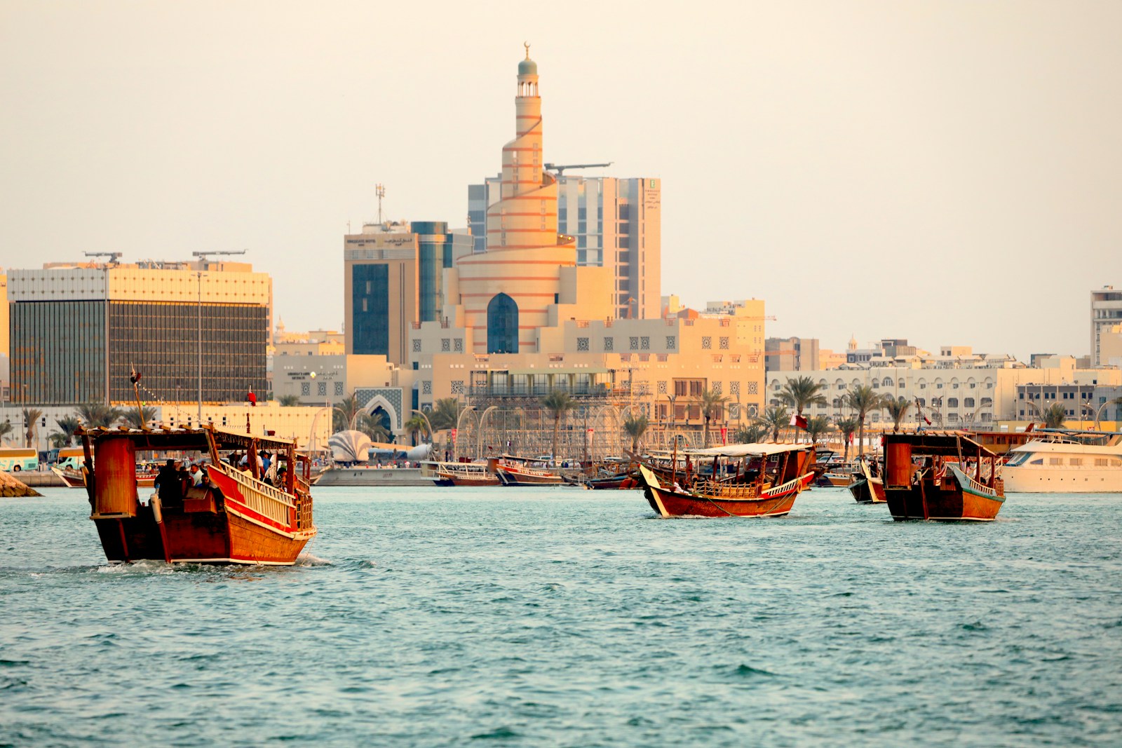 a group of boats in a body of water with buildings in the background